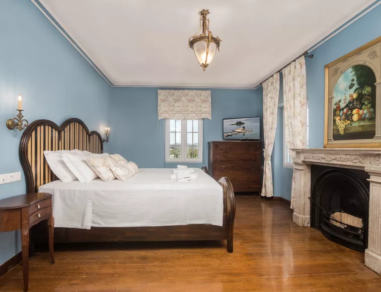 Wooden floors, an impressive fireplace and oak furniture make a contrast with the pale blue walls reminding of the Ionian Sea, in master bedroom of the 2nd floor.