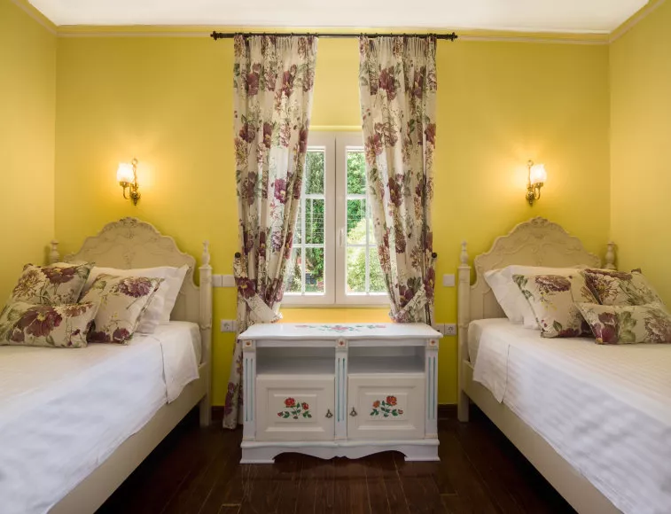 Twin bedroom in vivid yellow, harmoniously blending with the window view to the garden!